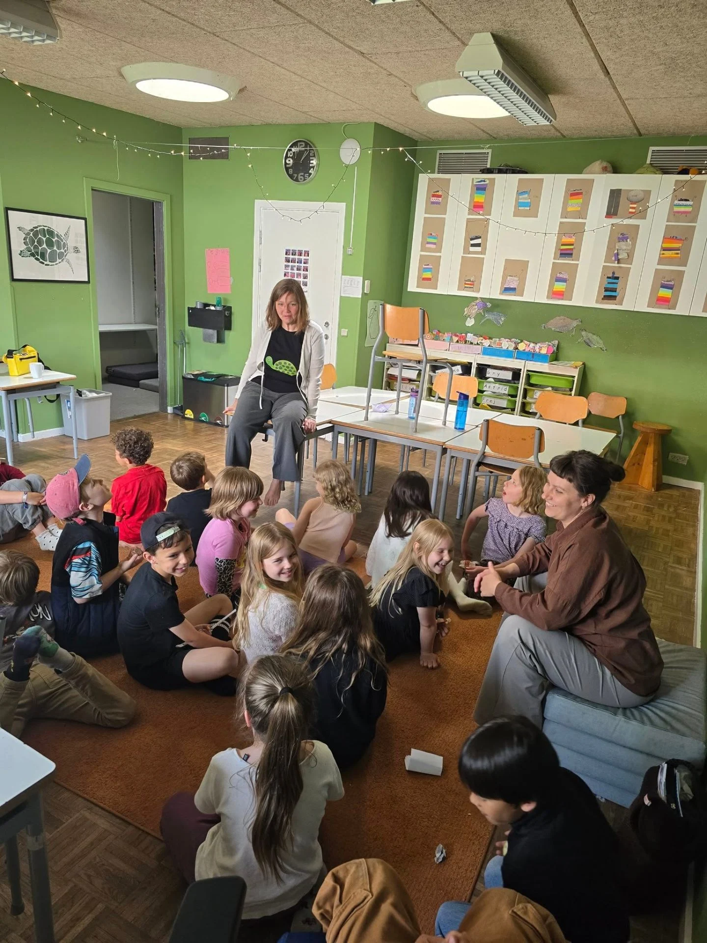 Børn og lærere samlet på gulvet i et klasselokale på Børnenes Friskole